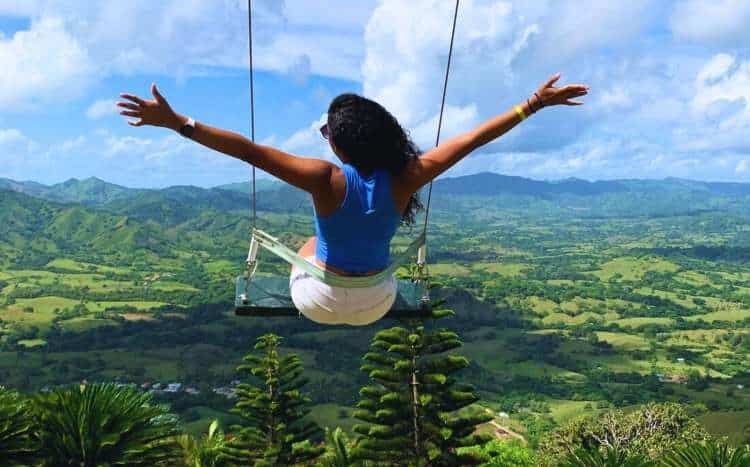 Person swinging above lush mountains at Mount Redonda, Dominican Republic