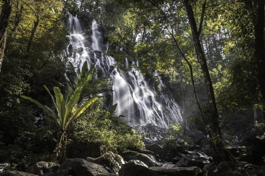 Drone view of winding river and cascading waterfalls at 27 Charcos, surrounded by dense tropical forest in the Dominican Republic