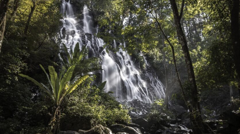 Drone view of winding river and cascading waterfalls at 27 Charcos, surrounded by dense tropical forest in the Dominican Republic