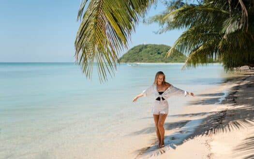 Tropical beach in the Dominican Republic with palm trees, white sand, and turquoise ocean waves under a sunny blue sky.