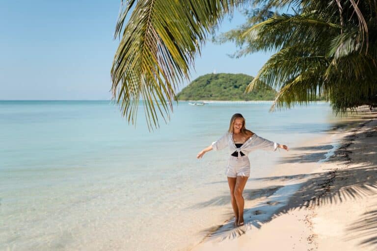 Tropical beach in the Dominican Republic with palm trees, white sand, and turquoise ocean waves under a sunny blue sky.