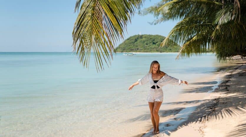 Tropical beach in the Dominican Republic with palm trees, white sand, and turquoise ocean waves under a sunny blue sky.