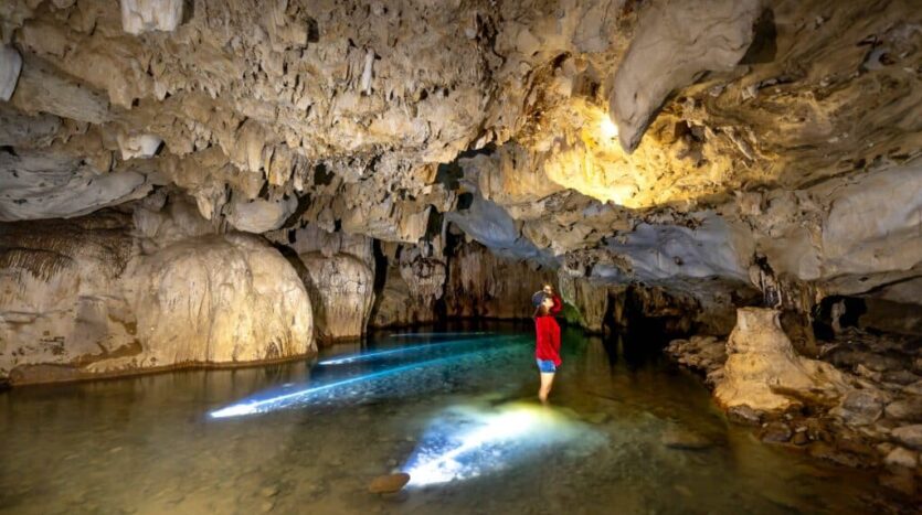elunkers exploring a deep cave chamber in the Dominican Republic with helmets and headlamps