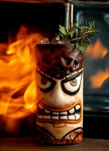 Ingrédients secs pour la Mamajuana, y compris des écorces d'arbre, des herbes et des épices, disposés à côté d'une bouteille en verre vide.