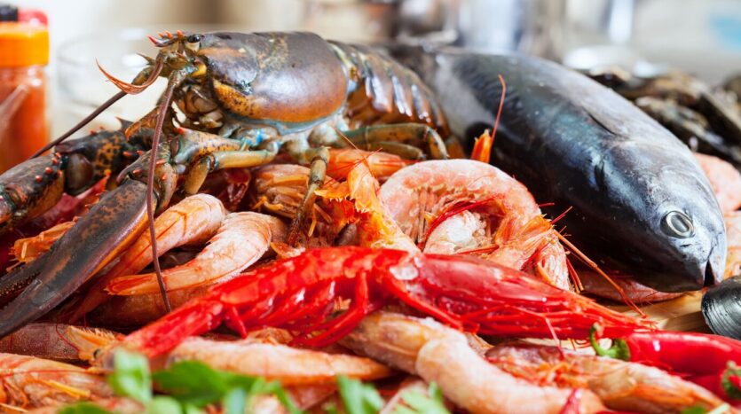 Grilled Dominican seafood cooking over open flames at a beachside food shack.