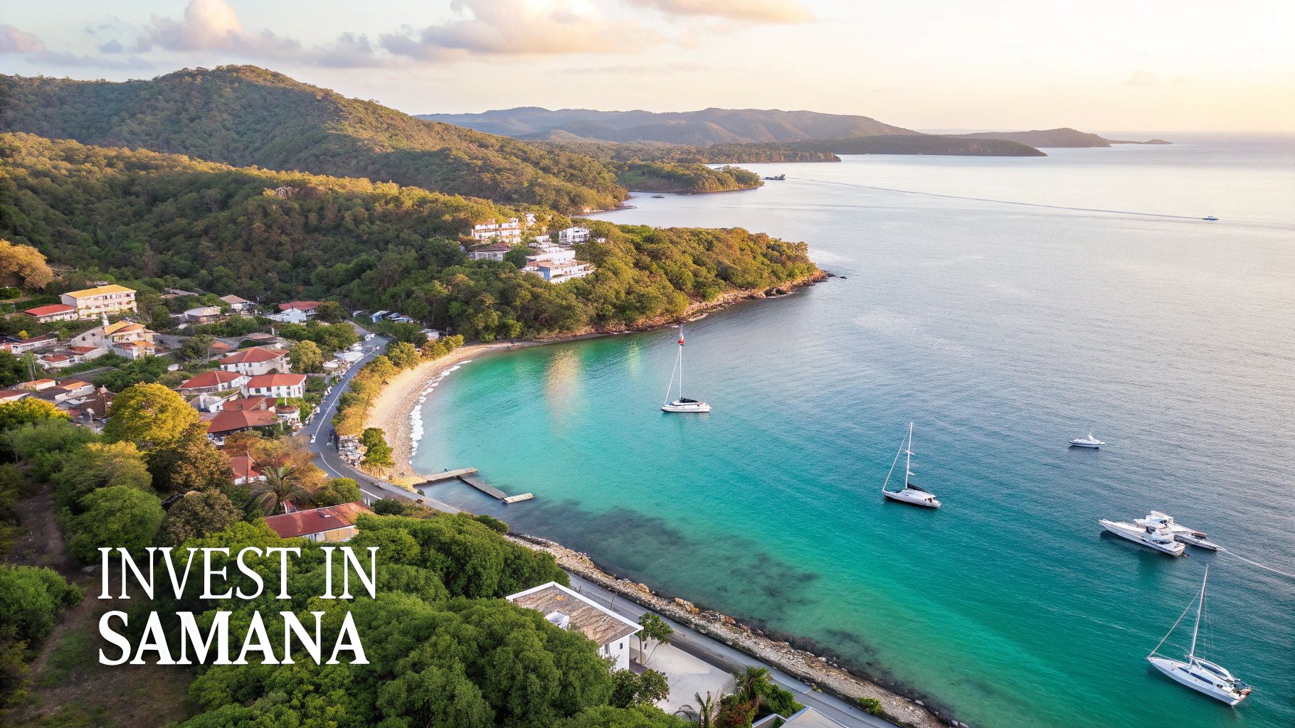 Aerial view of a picturesque bay in Samana with a coastal town, lush hills, sailboats, and turquoise water.